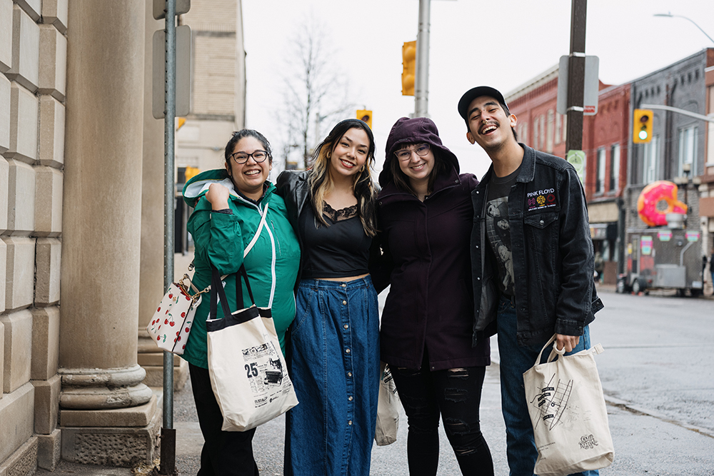 4 young adults standing together on a street