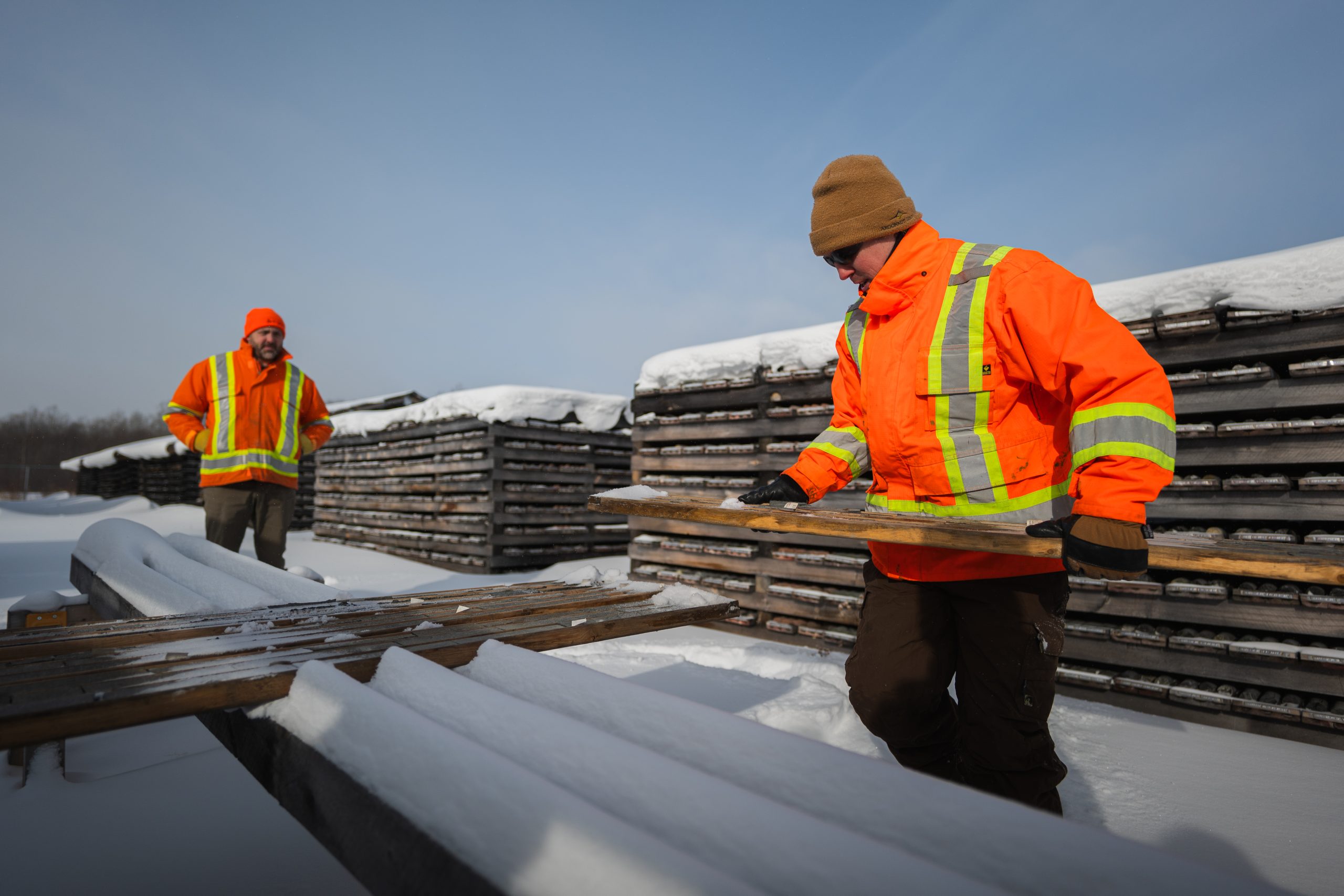 two men in orange holding board